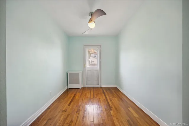 a view of empty room with wooden floor and window