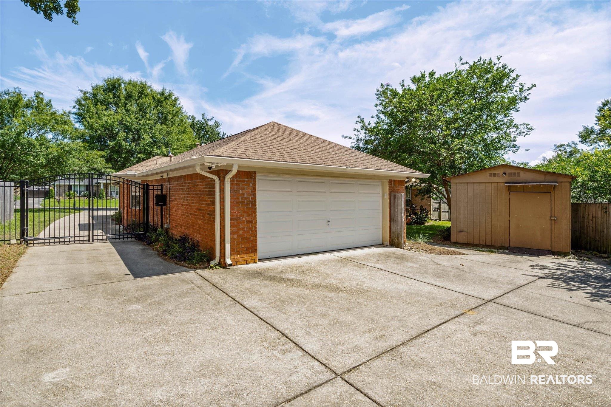 7410 Smithfield Road East Mobile, AL 36695 - Photo 19 of 24 Brick exterior home featuring an attached garage with a white garage door, concrete driveway, and a separate storage shed