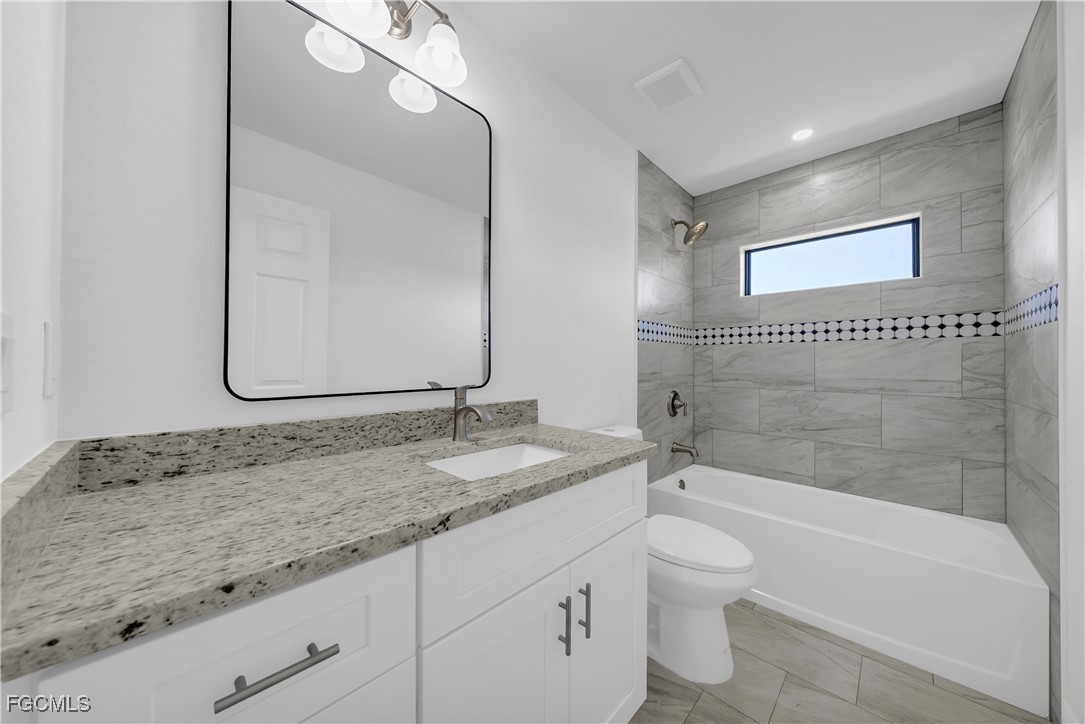 7979 16th Place LaBelle, FL 33935 - Photo 18 of 36 a bathroom with a granite countertop sink a toilet and bathtub