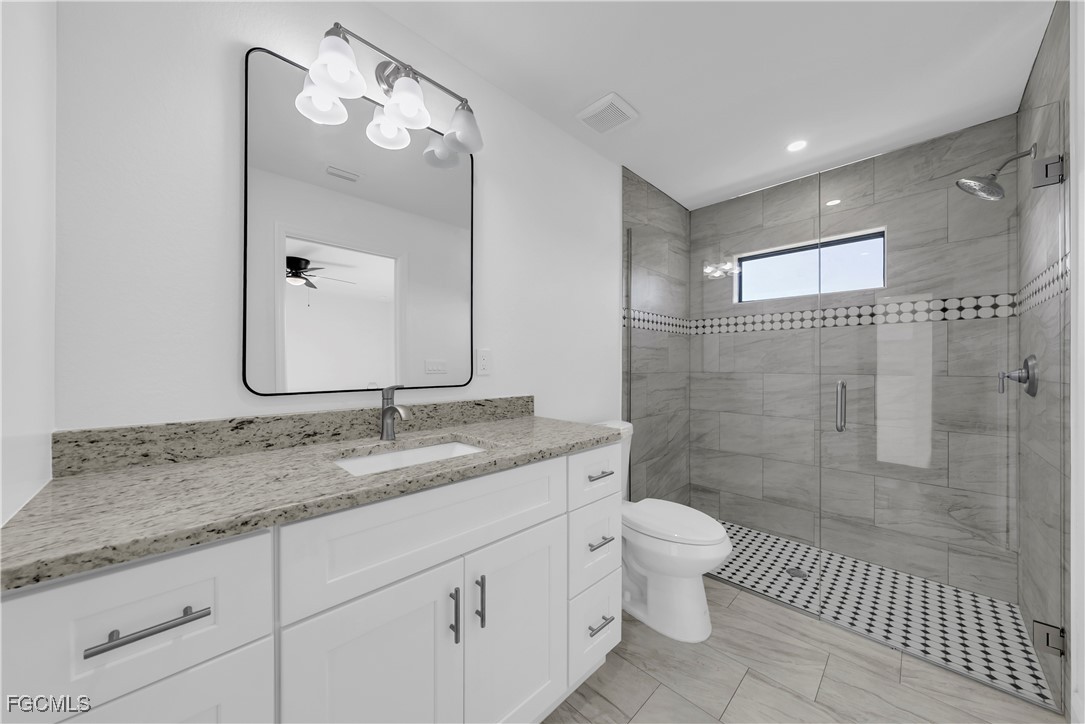 7979 16th Place LaBelle, FL 33935 - Photo 21 of 36 a bathroom with a granite countertop sink a toilet a mirror and shower