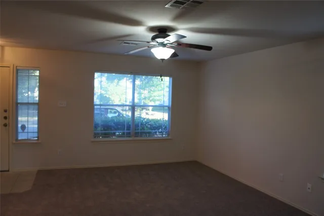 en empty room with window and chandelier fan