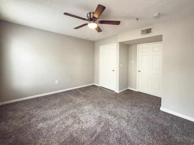 an empty room with closet and a ceiling fan