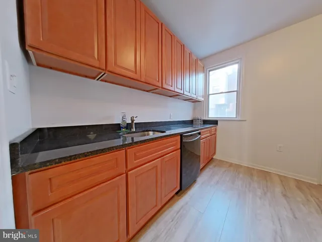 a kitchen with granite countertop wooden cabinets a sink and dishwasher