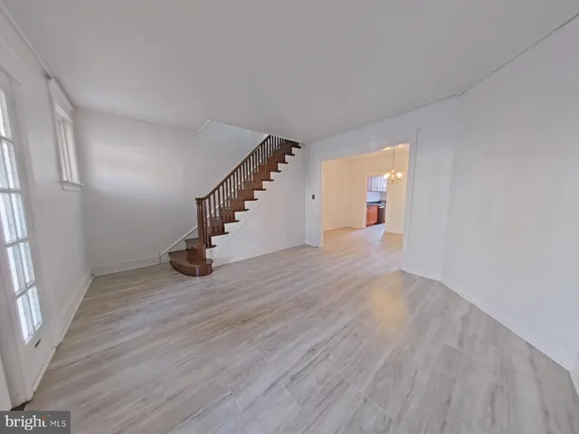 a view of an empty room with wooden floor and stairs