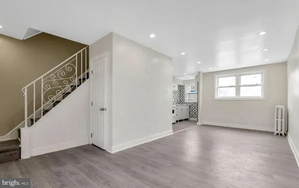 a view of an empty room with wooden floor and stairs