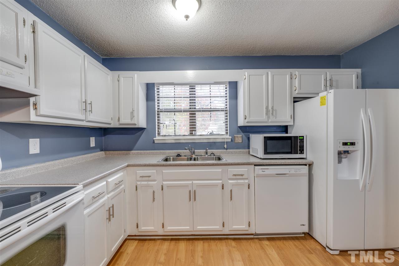 5757 3 Oaks Drive Raleigh, NC 27612 - Photo 5 of 20 a kitchen with white cabinets and white appliances