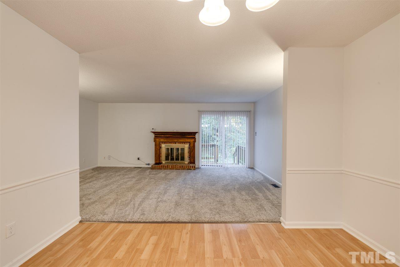 5757 3 Oaks Drive Raleigh, NC 27612 - Photo 7 of 20 a view of empty room with wooden floor and fireplace
