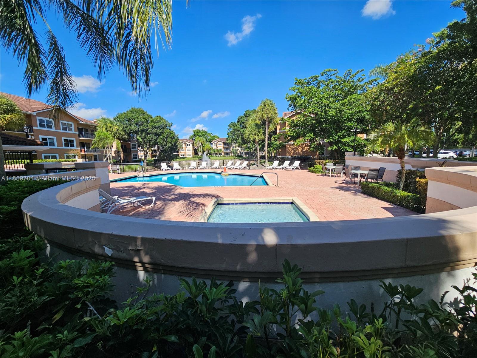 8701 Wiles Road, Unit 305 Coral Springs, FL 33067 - Photo 16 of 17 a small pool with lawn chairs under an umbrella