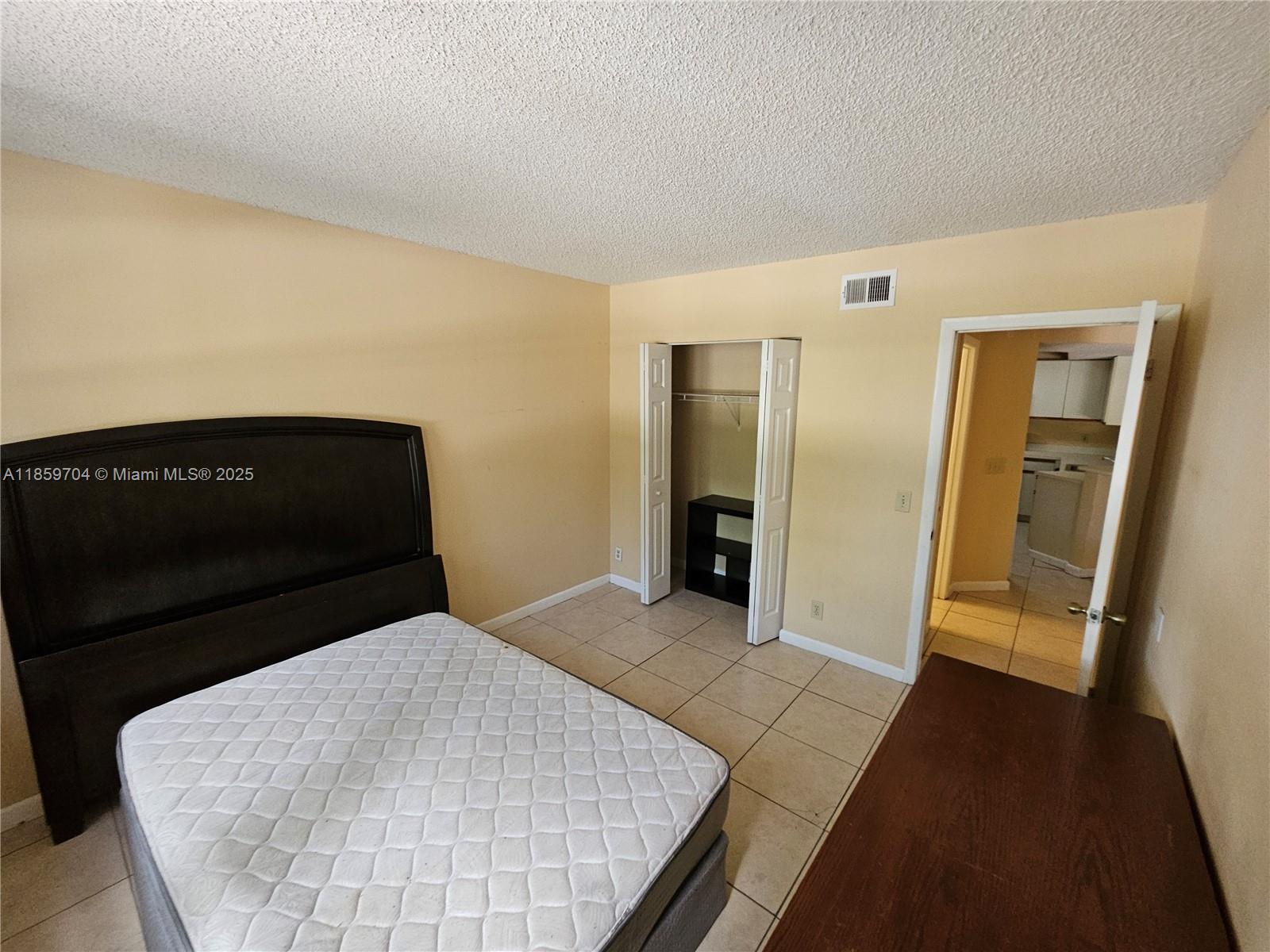 8701 Wiles Road, Unit 305 Coral Springs, FL 33067 - Photo 9 of 17 a bedroom with a bed and wooden floor