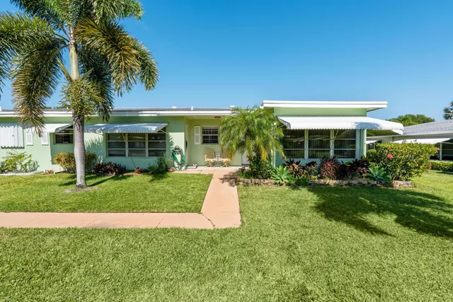a view of a house with a yard and potted plants