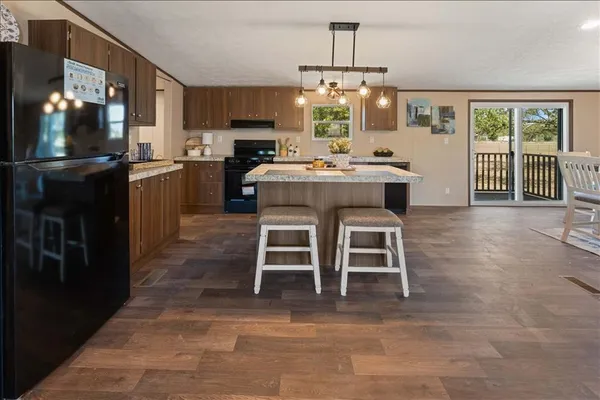 a view of a kitchen with kitchen island granite countertop cabinets a counter top space and stainless steel appliances