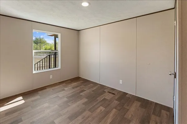 a view of an empty room with a window and hardwood floor