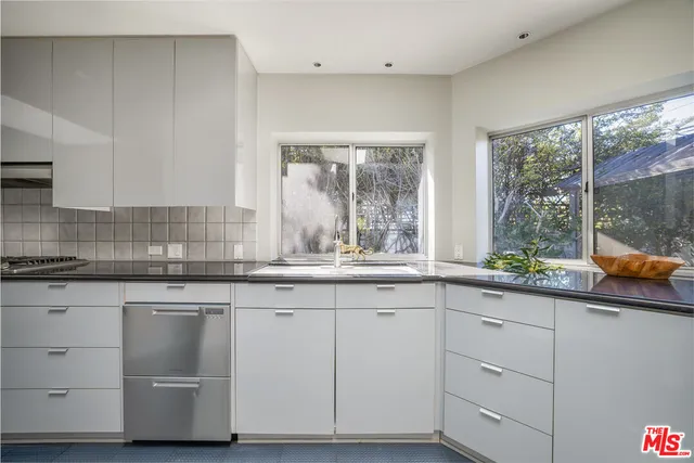 a kitchen with white cabinets and a window