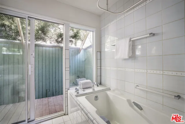 a bathroom with a tub a sink and glass door