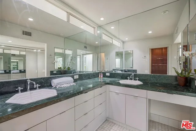 a bathroom with a granite countertop sink and a large mirror