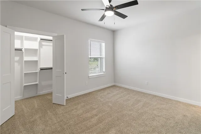 en empty room with ceiling fan and window
