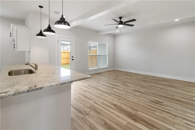a view of kitchen and empty room with wooden floor