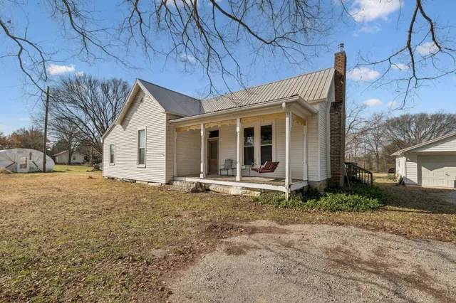 a view of a house with a yard and large tree