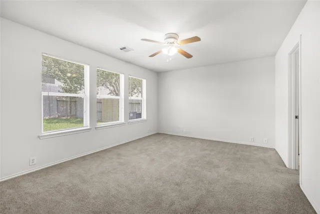 an empty room with windows and fan