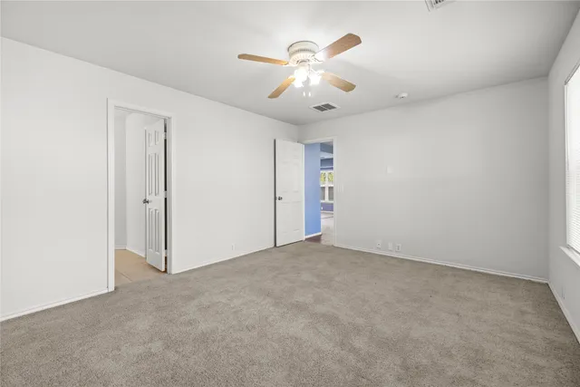 an empty room with fan and windows