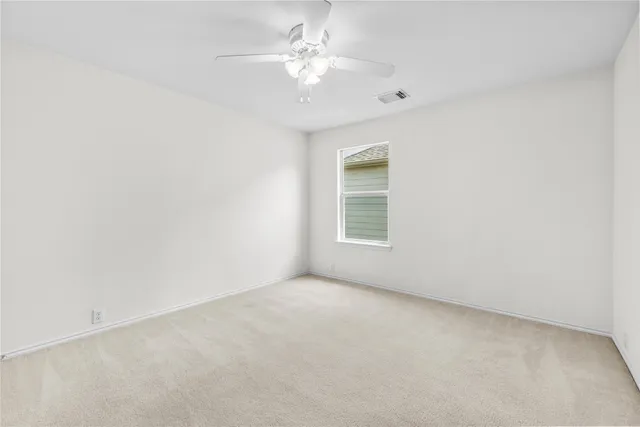 an empty room with a chandelier fan and windows