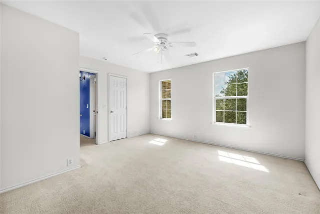an empty room with windows and ceiling fan