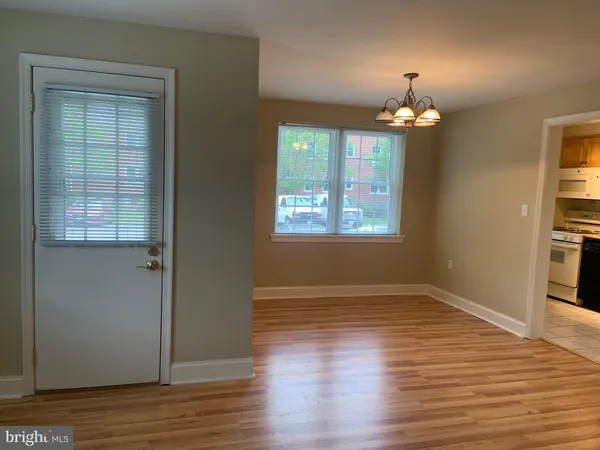an empty room with wooden floor chandelier and windows