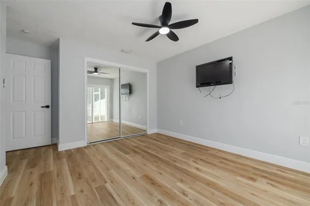 a view of empty room with wooden floor and fan