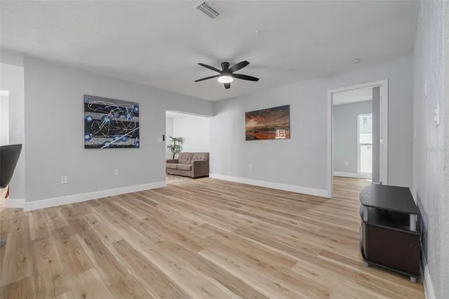 a view of empty room with wooden floor and fan