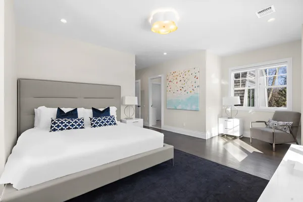 a bedroom with a bed a painting on the wall and a window