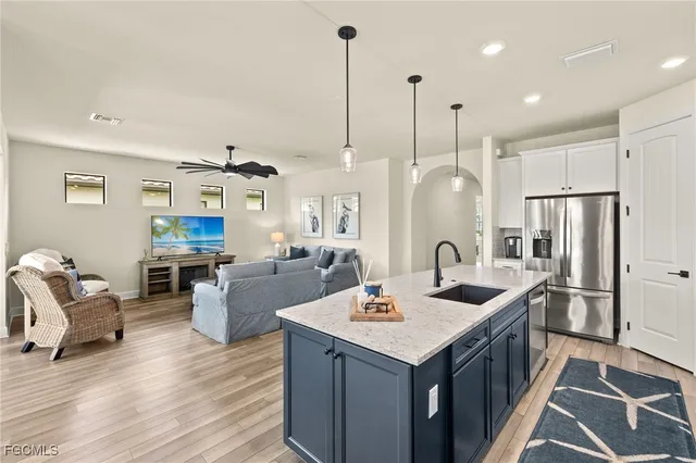 a open kitchen with stainless steel appliances granite countertop a sink a microwave a refrigerator and wooden floor