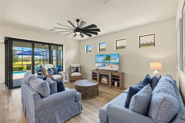 a living room with furniture a ceiling fan a fireplace and a large window