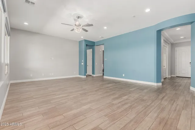 a view of an empty room with wooden floor and a ceiling fan
