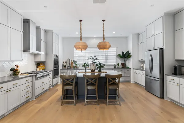 a kitchen with stainless steel appliances a dining table chairs stove and white cabinets