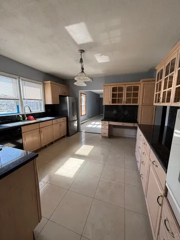 a living room with stainless steel appliances furniture a rug and a kitchen