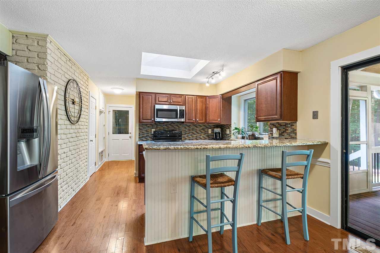 8609 Langtree Lane Raleigh, NC 27613 - Photo 8 of 30 a kitchen with stainless steel appliances kitchen island granite countertop a refrigerator a stove a microwave oven with a dining table and chairs