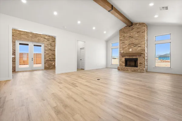 an empty room with wooden floor fireplace and windows