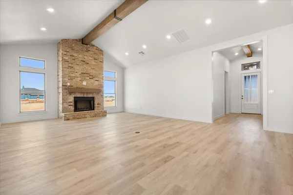 an empty room with wooden floor and fireplace