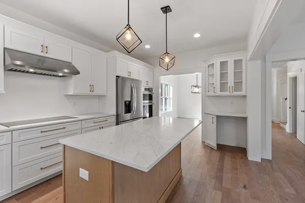 a kitchen with a center island refrigerator wooden floor and cabinets