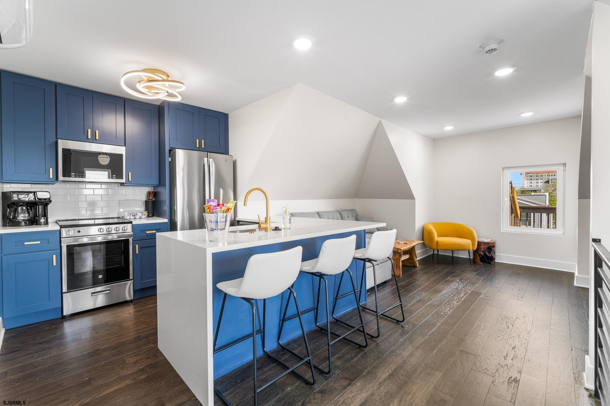 a kitchen with stainless steel appliances a stove a sink a refrigerator cabinets and wooden floor