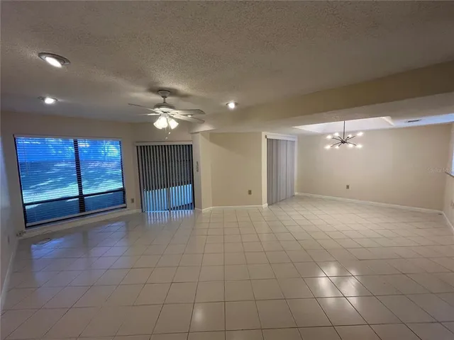 a view of an empty room with glass door and chandelier fan