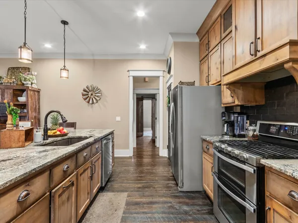 a kitchen with stainless steel appliances granite countertop a refrigerator a stove and a sink