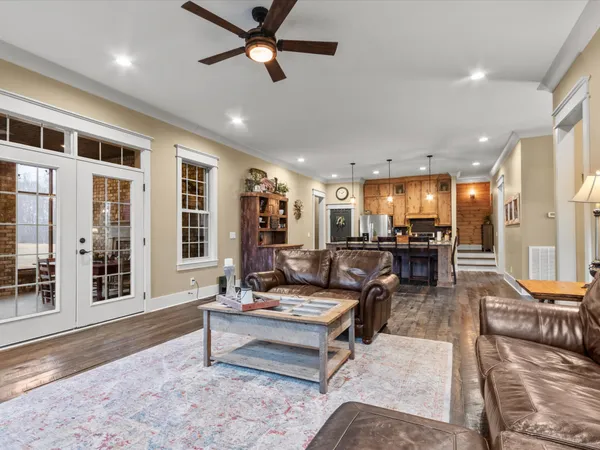a living room with furniture kitchen view and a wooden floor