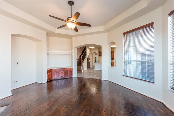 a view of a livingroom with wooden floor a ceiling fan and windows