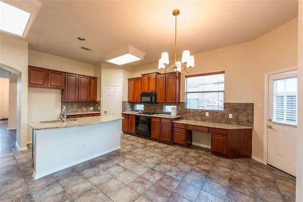 a large kitchen with kitchen island granite countertop a stove and a sink