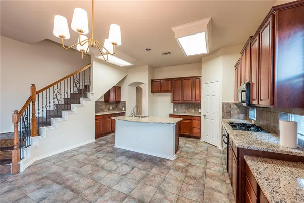 a kitchen with granite countertop a refrigerator a stove top oven a dining table and chairs