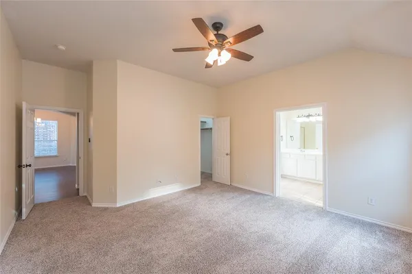 an empty room with a chandelier fan and windows