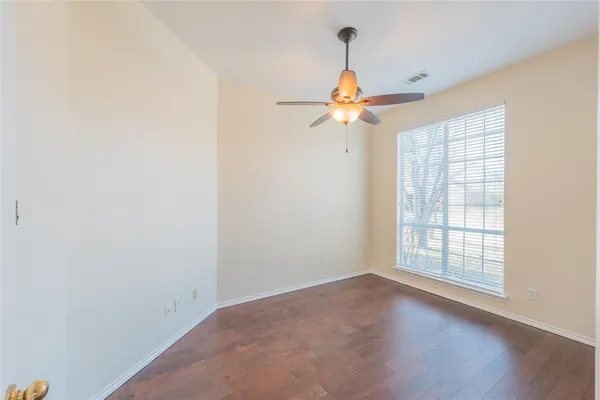 an empty room with windows and chandelier fan