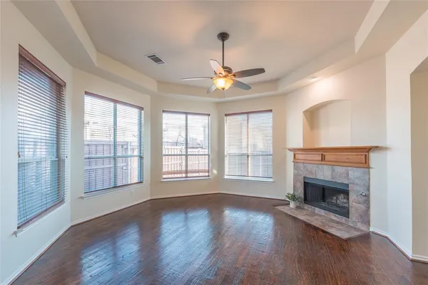 a view of an empty room with wooden floor fireplace and a window