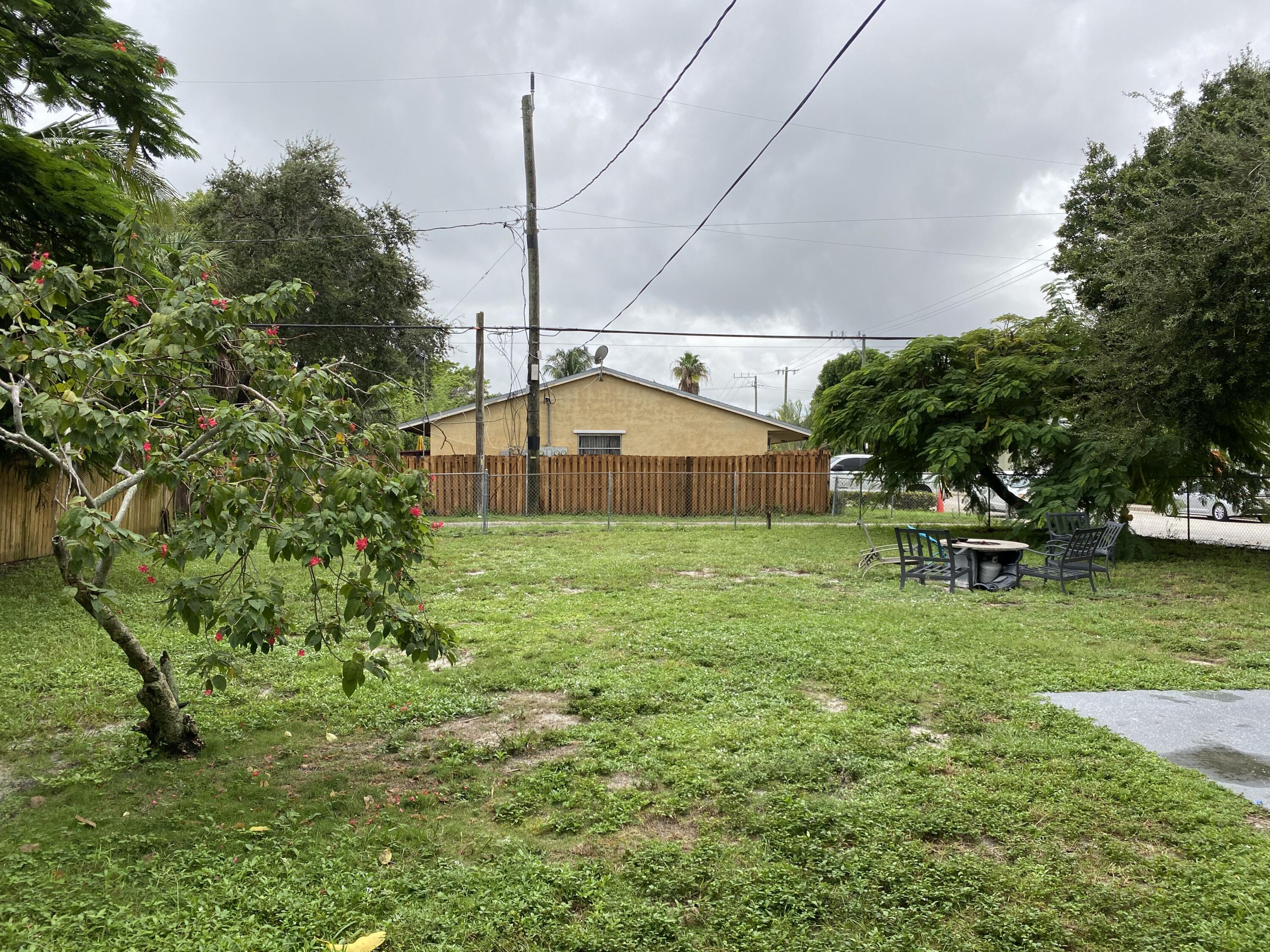301 South M Street, Unit 5 Lake Worth Beach, FL 33460 - Photo 4 of 17 a yellow house with trees in front of it